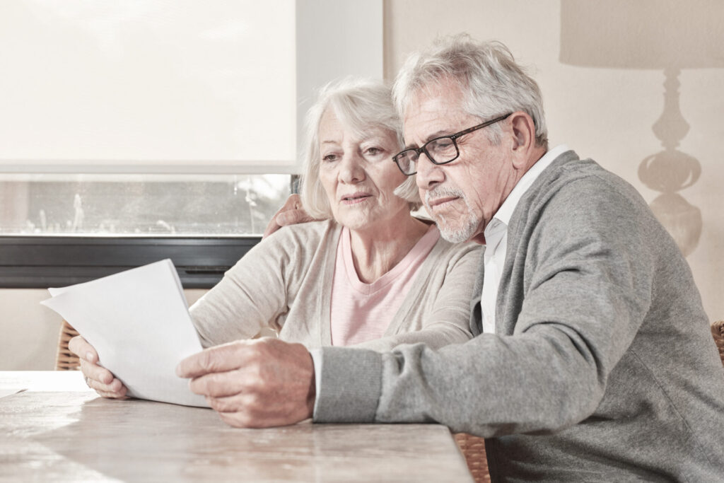Senioren Paar liest Unterlagen für die Bestattungsvorsorge.